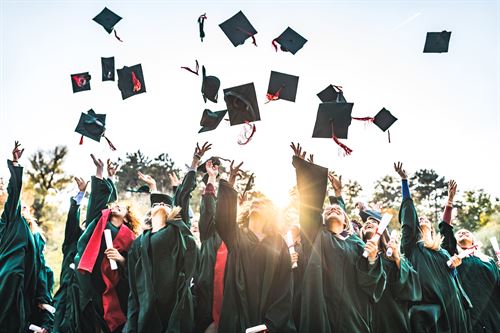 graduates tossing caps into air